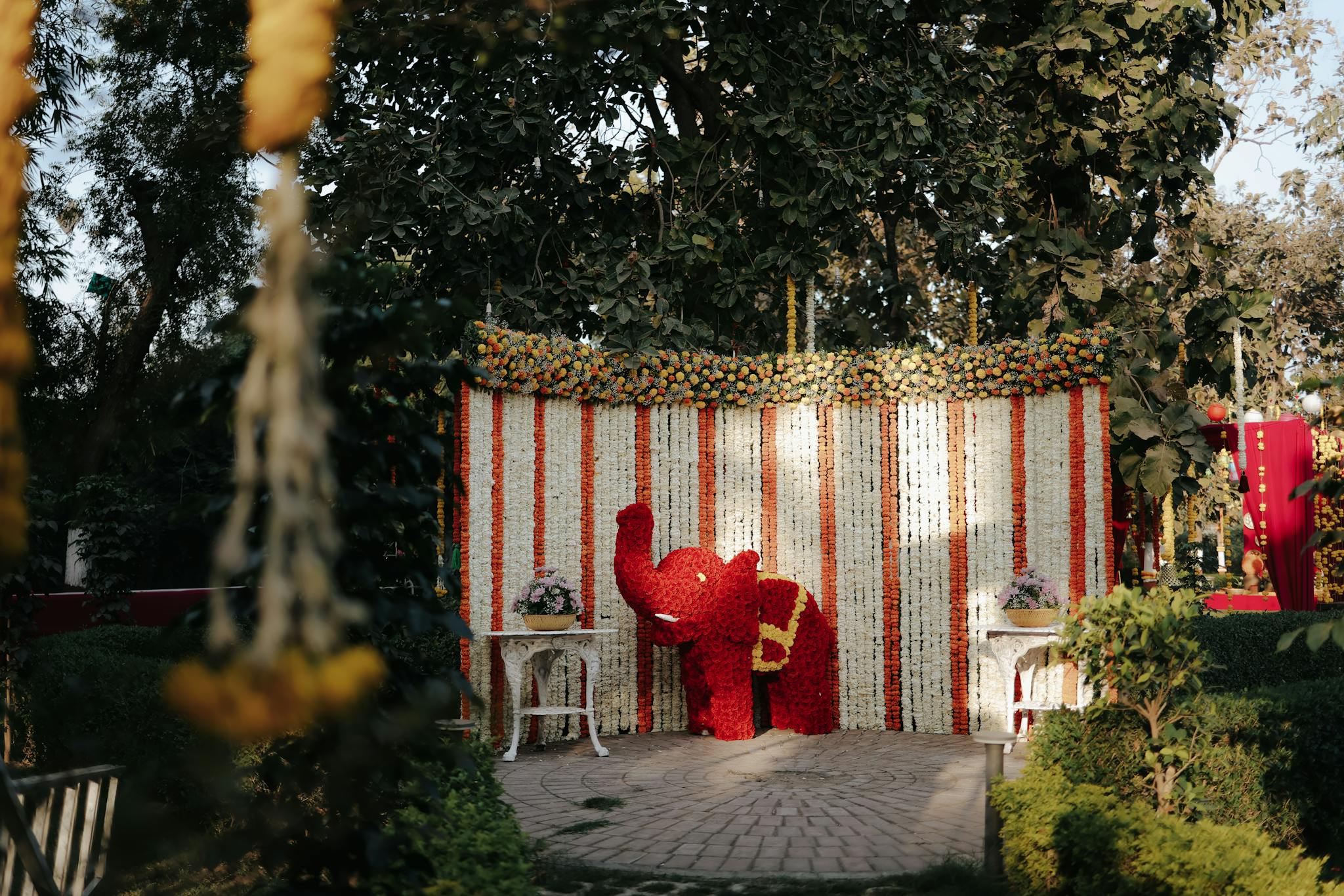 Vibrant floral elephant sculpture at a beautifully decorated outdoor event setting.