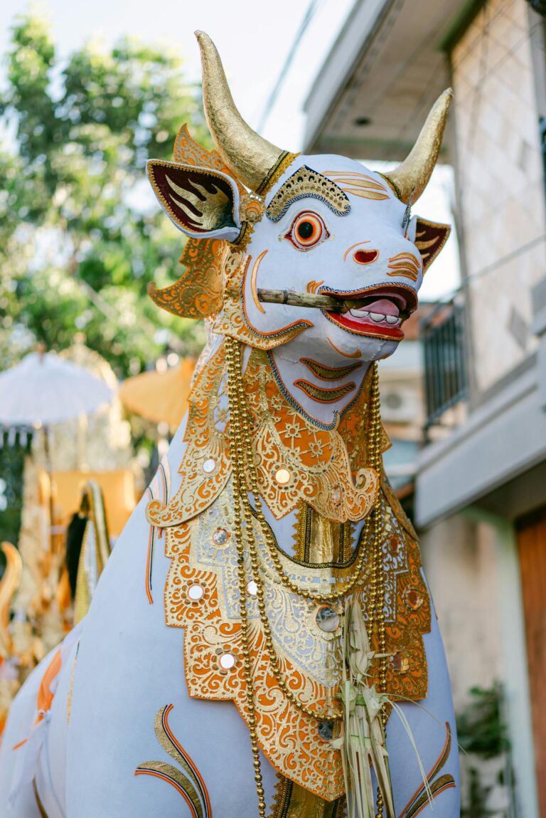Vibrant white bull statue adorned with golden decorations at an outdoor ceremony in Bali.